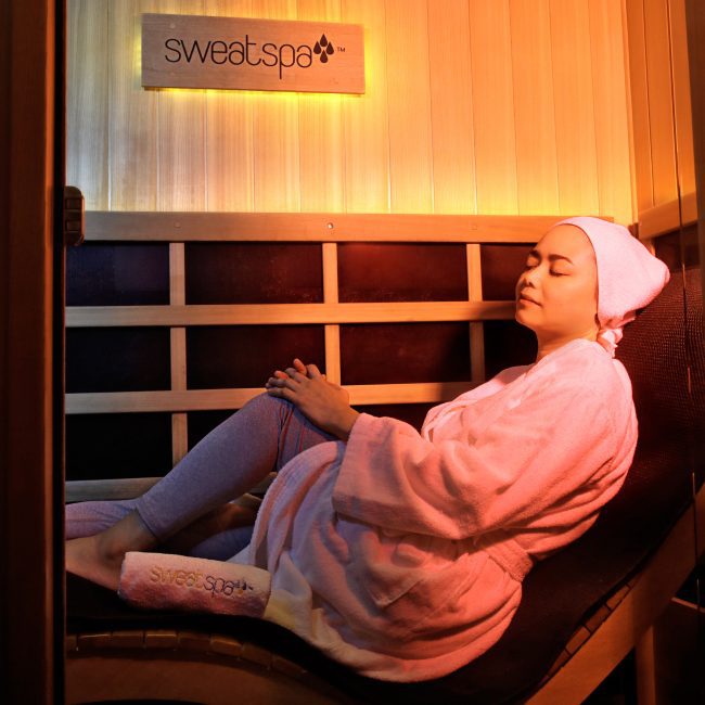 Woman relaxing in infrared sauna during self-care routine